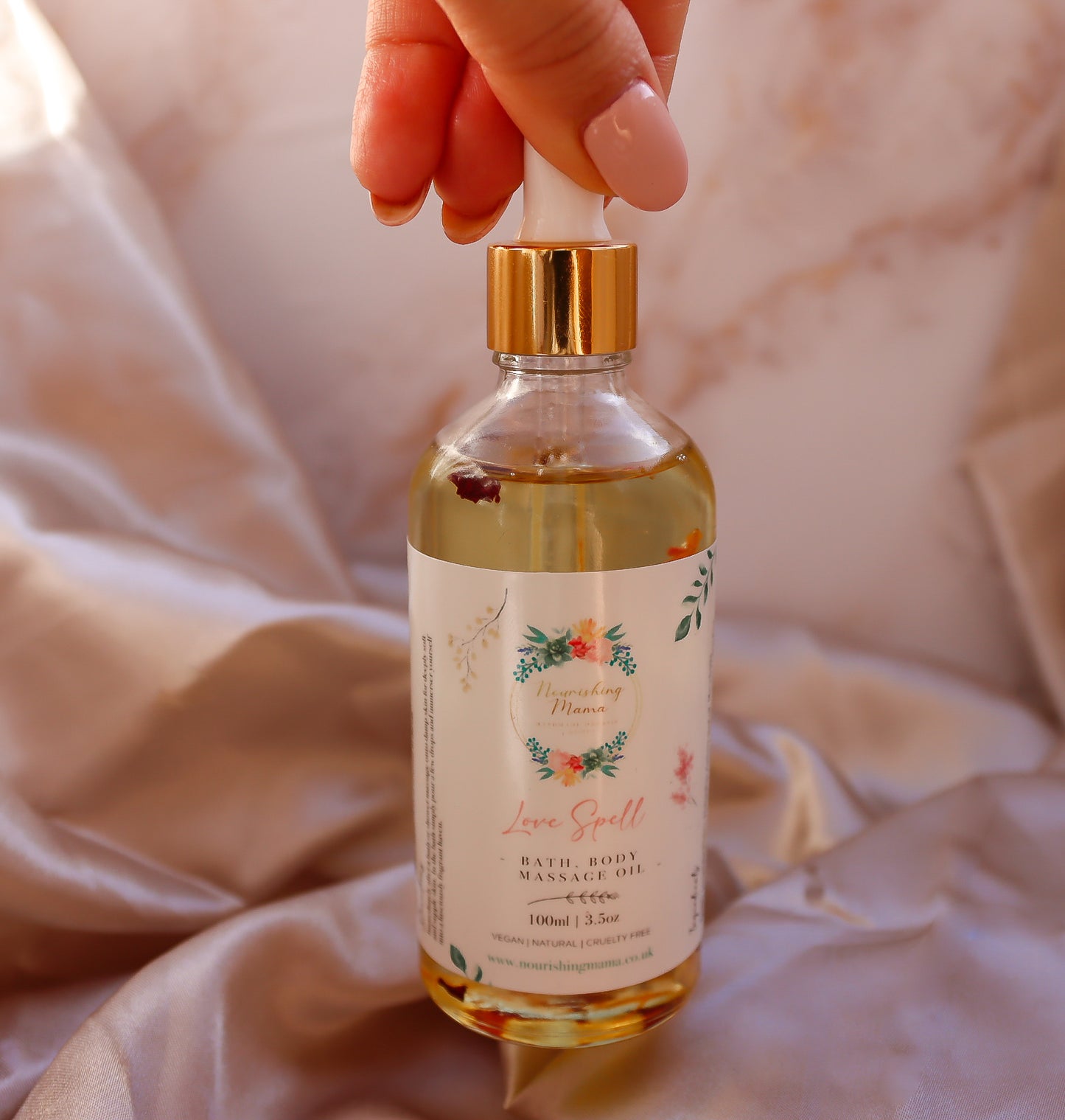 A hand holding a bottle of of Nourishing Mama Oil with the finger tips 